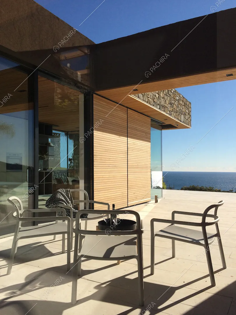 Sedie da esterno con tavolino sulla terrazza con pavimentazione in lastre di pietra e vista sul mare