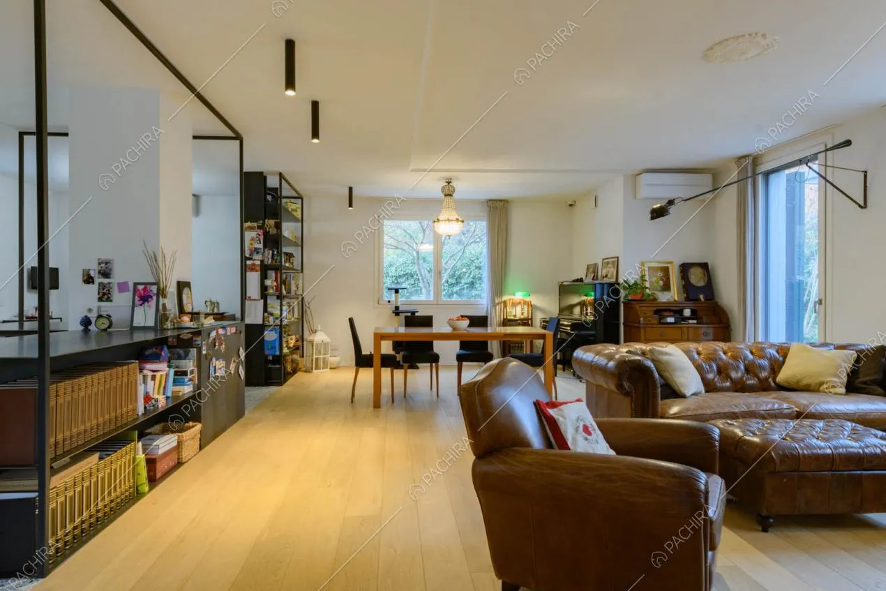 Grande sala con pavimento in parquet, divano e poltrone in pelle marrone vintage