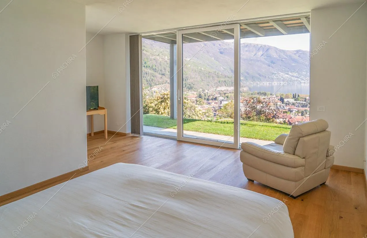 Camera da letto matrimoniale con pavimento in parquet, pareti bianche e porta-finestra scorrevole