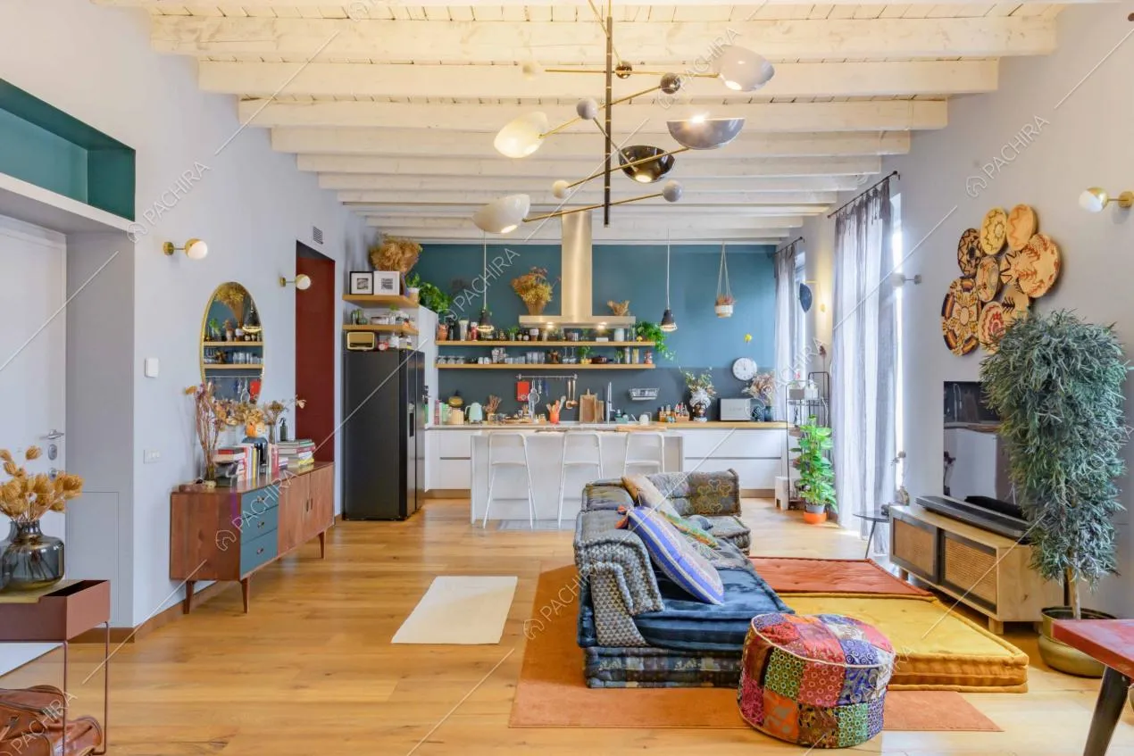 Ampio salone con pavimento in parquet di rovere, travi in legno a vista e cucina con isola