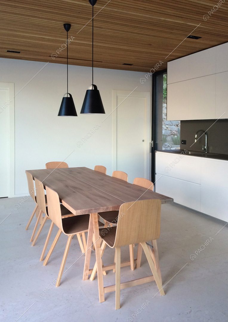 Tavolo da pranzo in legno nella cucina dalle pareti bianche con fornelli a induzione