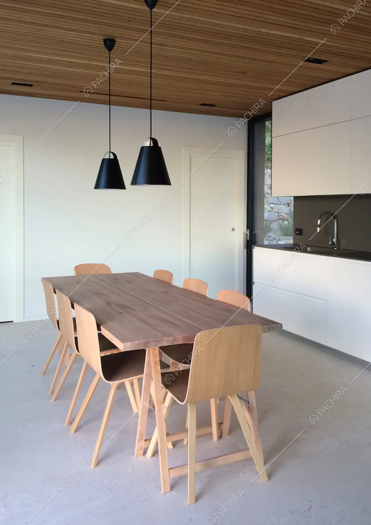 Tavolo da pranzo in legno nella cucina dalle pareti bianche con fornelli a induzione