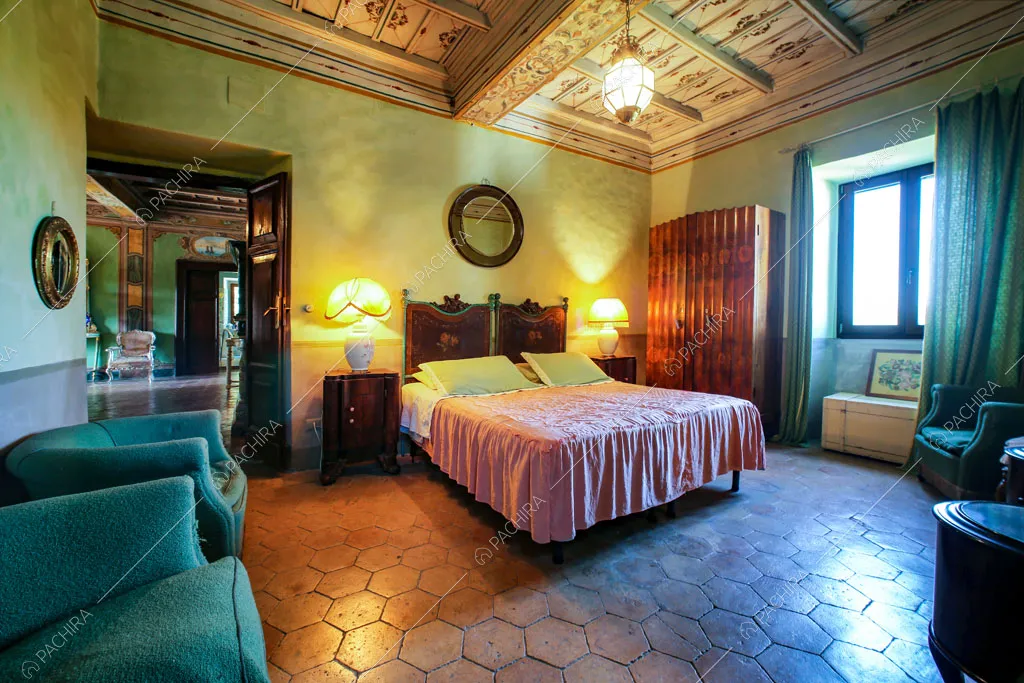 Camera da letto matrimoniale con pavimento in cementine e vista sul salotto con camino