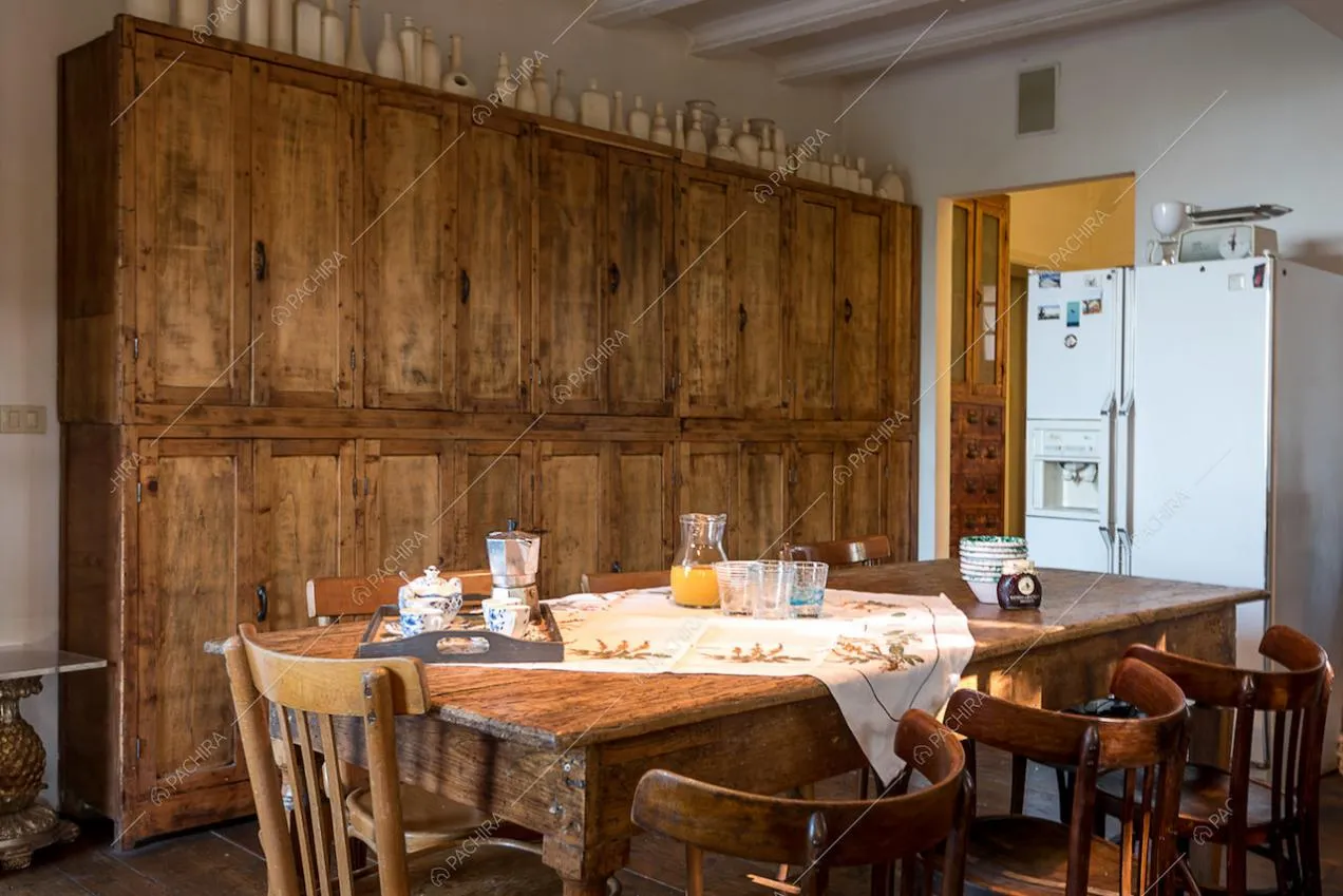 Tavolo da pranzo in legno nella cucina con credenza, pareti bianche e soffitto con travi a vista
