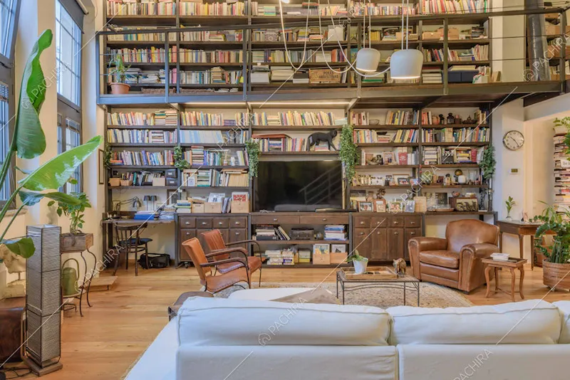 Divano bianco nel salotto con poltrone vintage e vista sulla libreria a parete