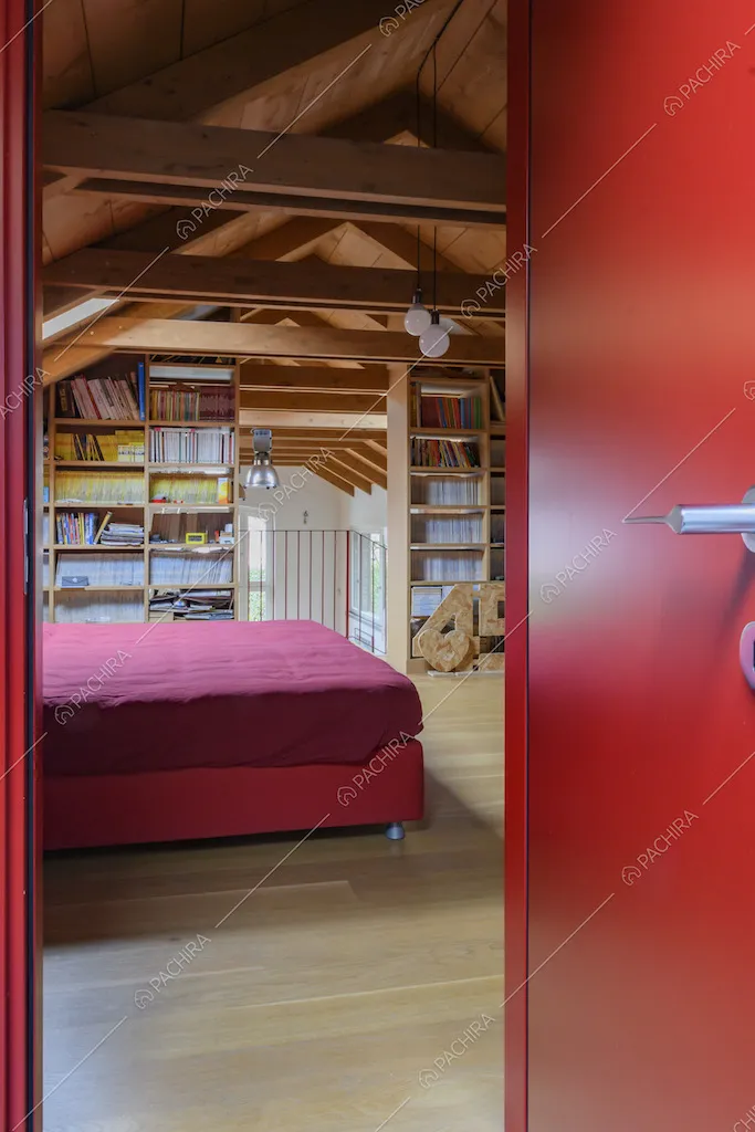 Porta rossa della camera da letto matrimoniale con pavimento in parquet e libreria