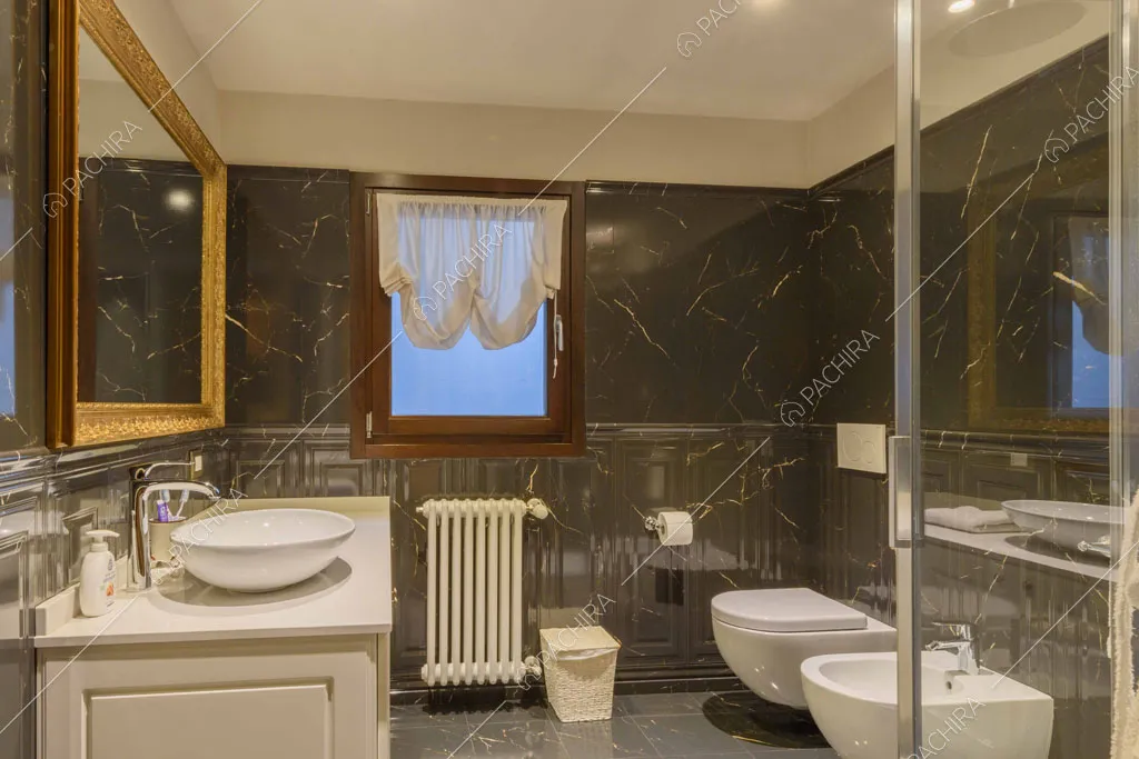 Grande bagno con marmo nero su pavimento e pareti