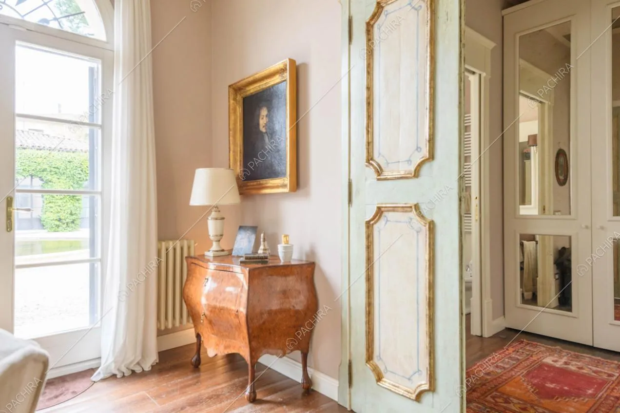 Porta con boiserie nella luminosa zona living con pavimento in parquet e vista sul giardino