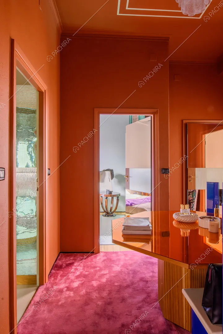 Moquette fucsia come pavimento della sala dalle pareti arancioni e con tavolo ottagonale