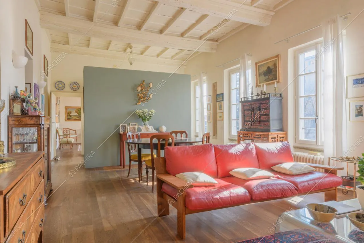 Pavimento in parquet e pareti bianche nella luminosa zona living con divano rosso