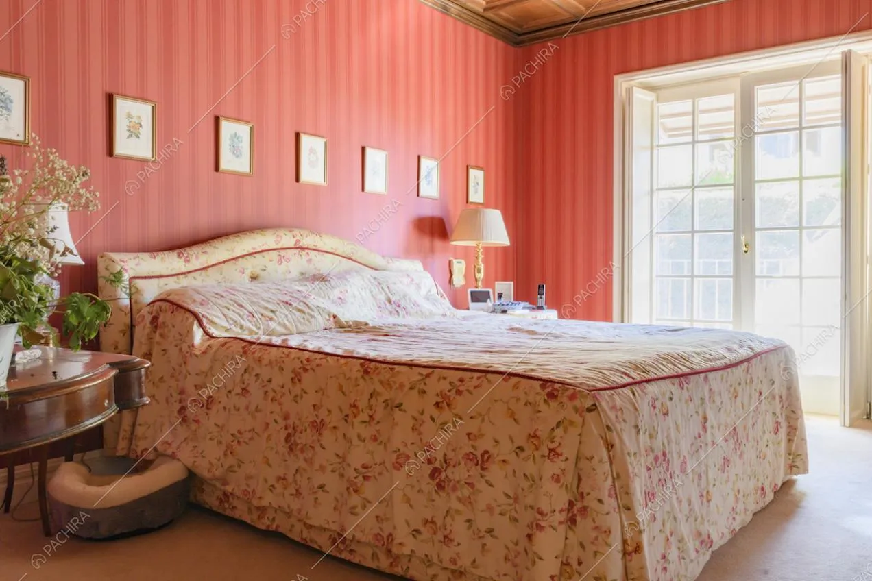 Letto matrimoniale con testiera in tessuto e quadretti appesi alla parete