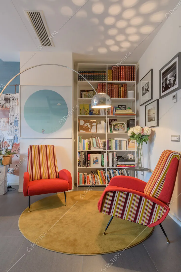 Poltrone colorate, lampada di design e libreria nella luminosa zona living