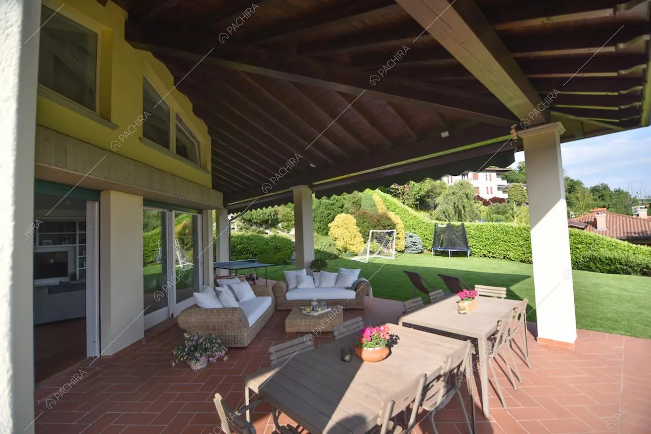 Veranda con travi a vista, tavoli con sedie e divani da esterno