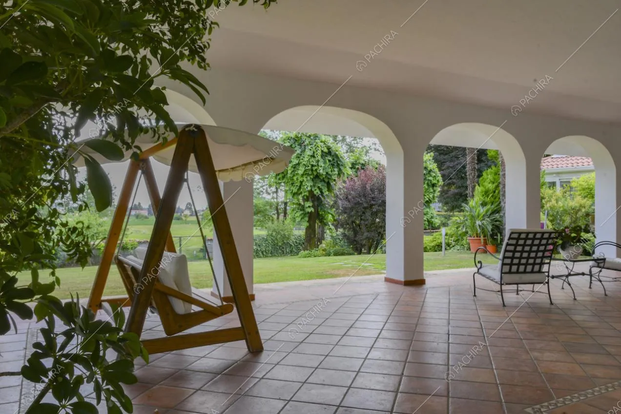 Nella veranda dal soffitto bianco dondolo e poltrone da esterno