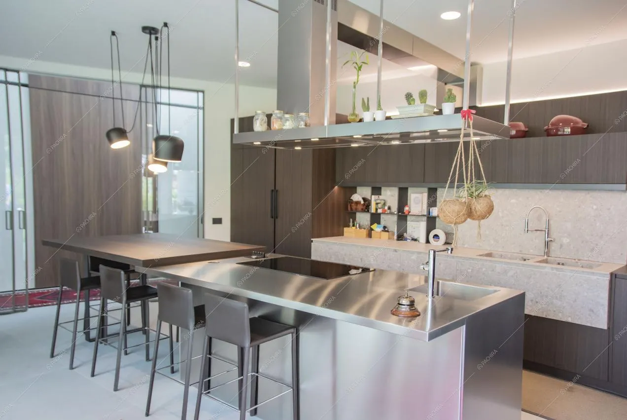 Cucina con isola in acciaio e in legno, fornelli a induzione e sgabelli