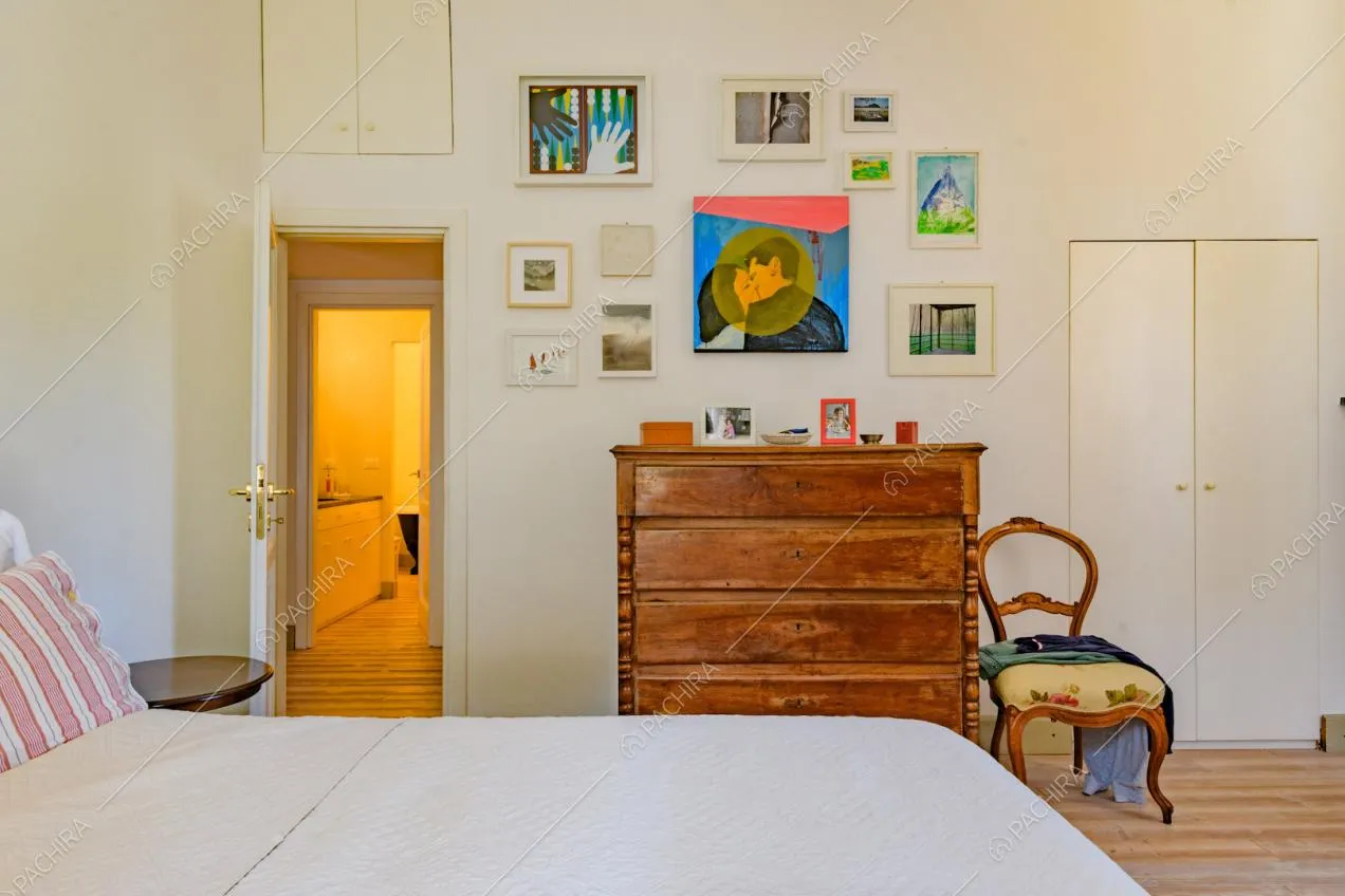 Camera da letto con pavimento in parquet, pareti bianche e bagno privato