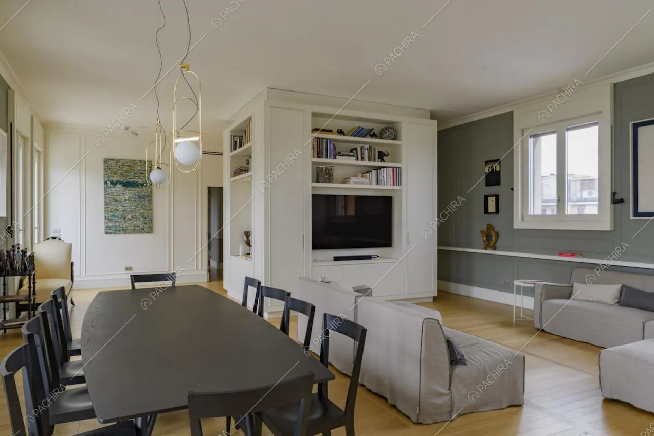 Sala con tavolo nero, pavimento in parquet, pareti bianche con boiserie e lampade di design