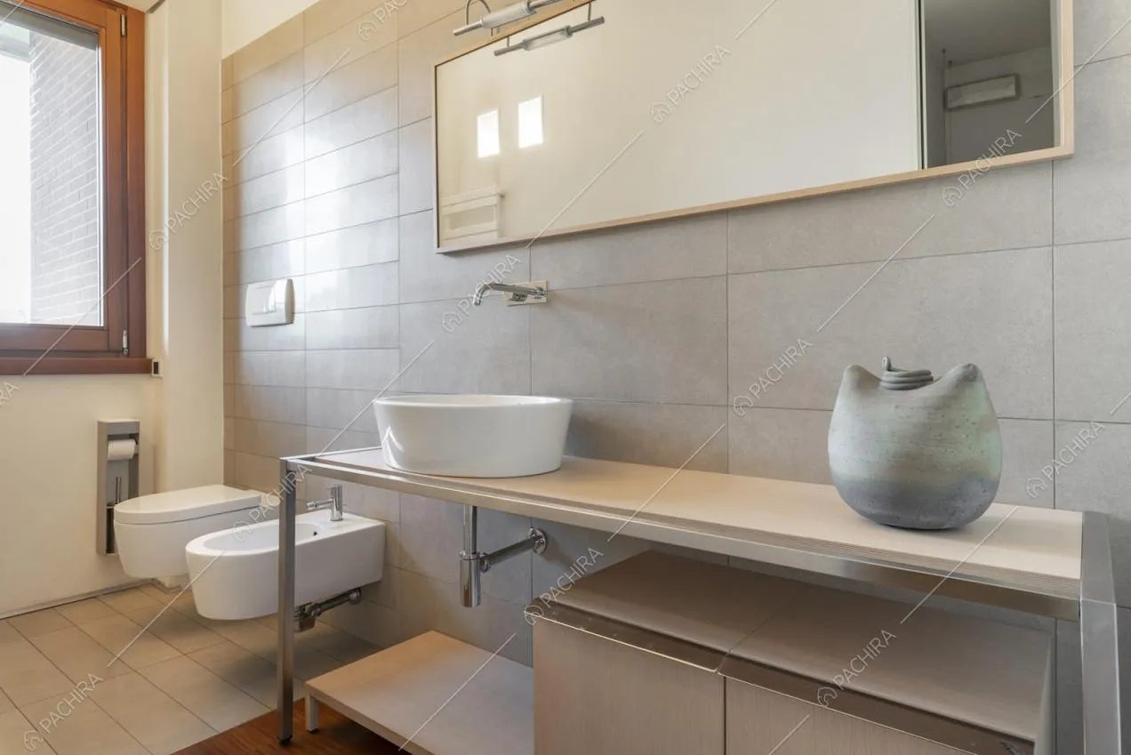 Bagno con pareti e pavimento rivestiti in piastrelle chiare