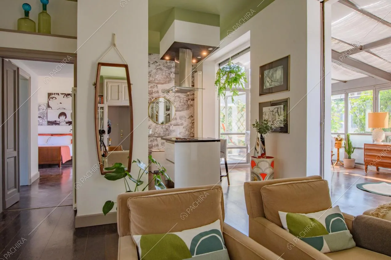 Poltrone nella zona living con carta da parati, soffitto verde e veranda