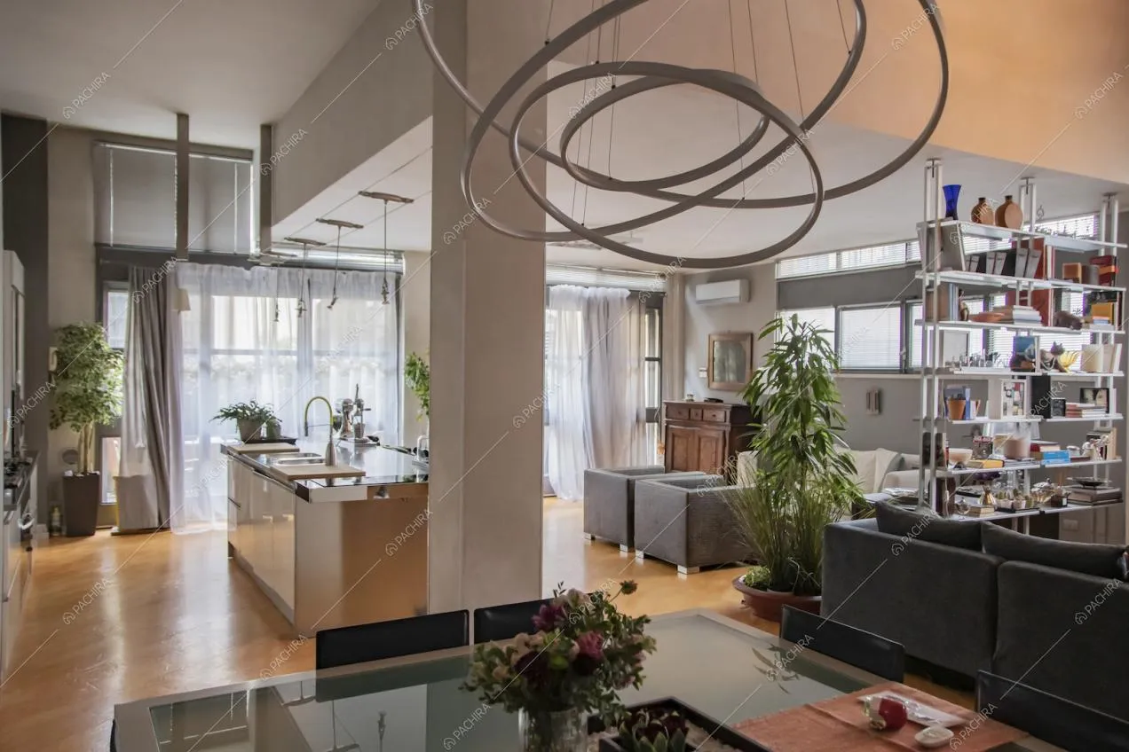 Tavolo da pranzo di design e vista sull'isola della cucina con fornelli a gas e salotto