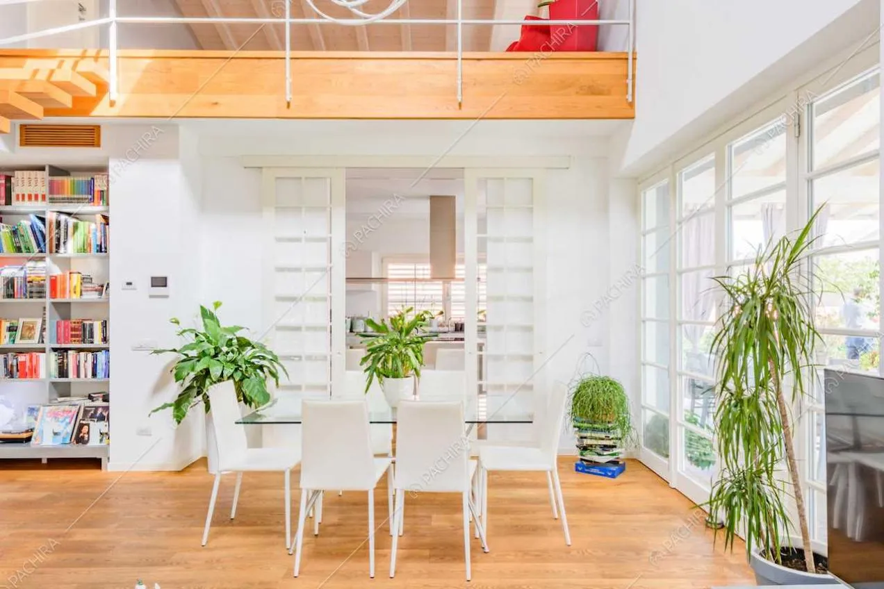 Zona living con pavimento in parquet, pareti bianche e porte-finestre
