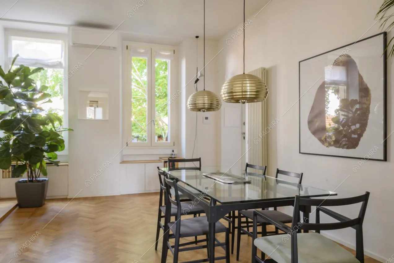 Tavolo da pranzo in vetro con sedie nere e lampade a sospensione