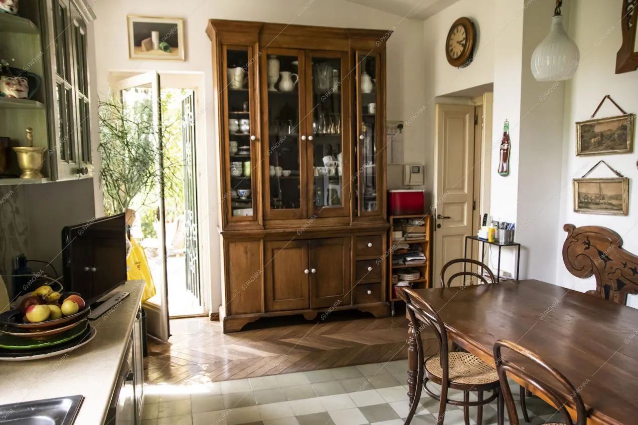 Cucina con tavolo da pranzo in legno e pavimento in parquet a spina di pesce e in piastrelle bianche e verdi