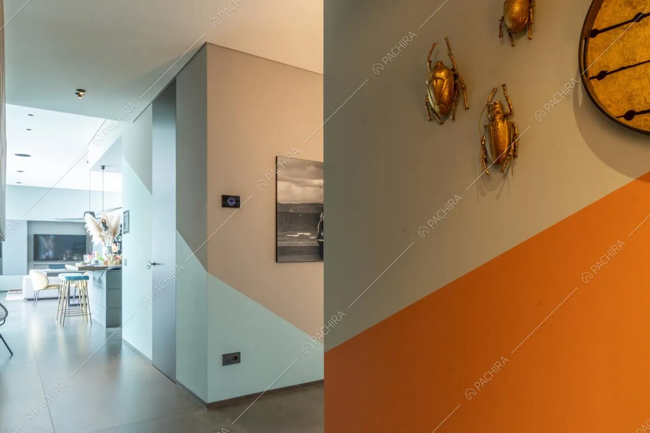 Corridoio con pareti grigie, azzurre e arancioni e vista sulla zona living