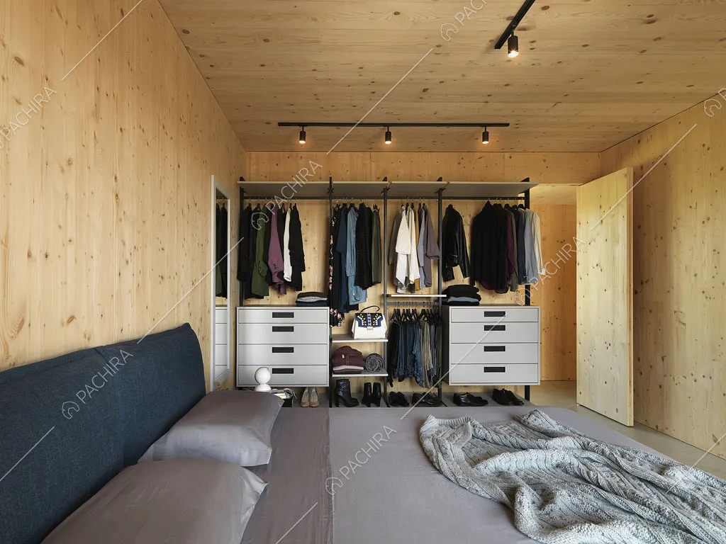 Letto matrimoniale nella camera con faretti sul soffitto in legno e armadio