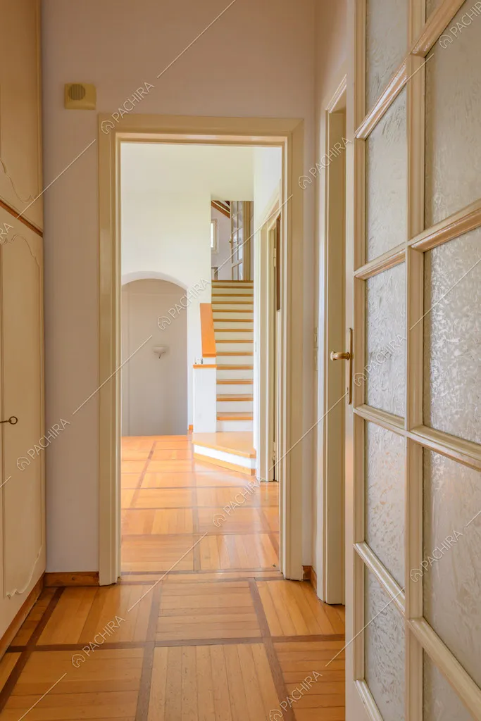 Porta a vetri bianca nel corridoio con pavimento in parquet e vista sulle scale