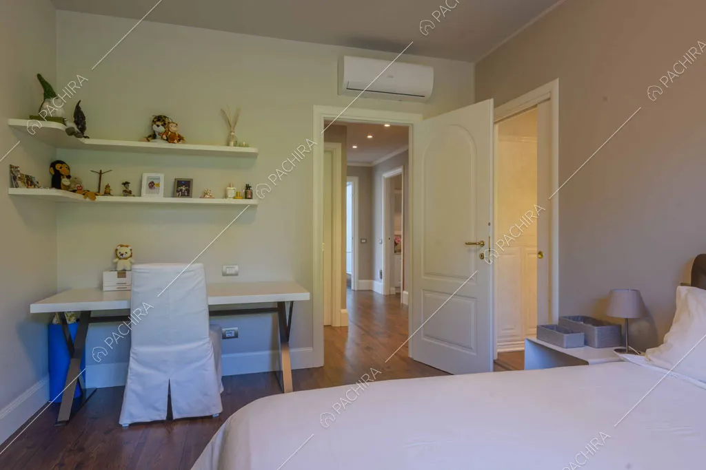 Camera con letto matrimoniale, porta bianca con boiserie e scrivania