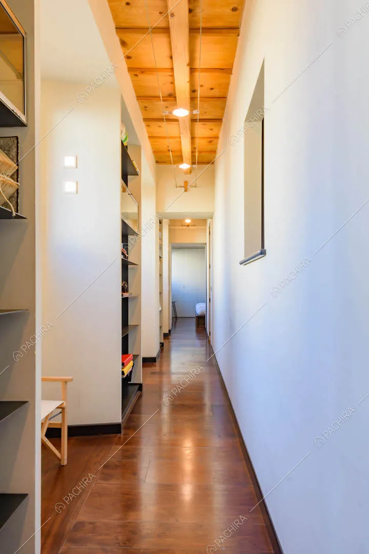 Lungo corridoio con pareti bianche e pavimento in parquet