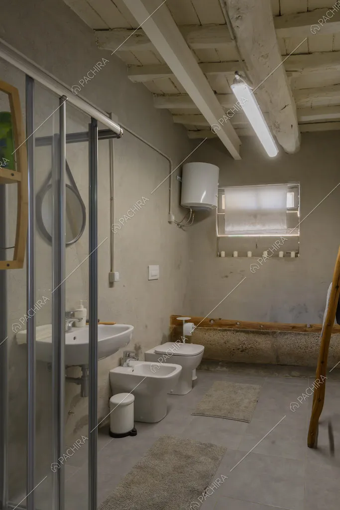 Bagno con soffitto in travi bianche a vista e box doccia