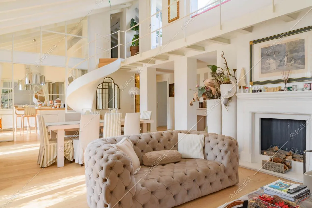 Divano beige nella zona living con camino e vista sulla cucina con penisola