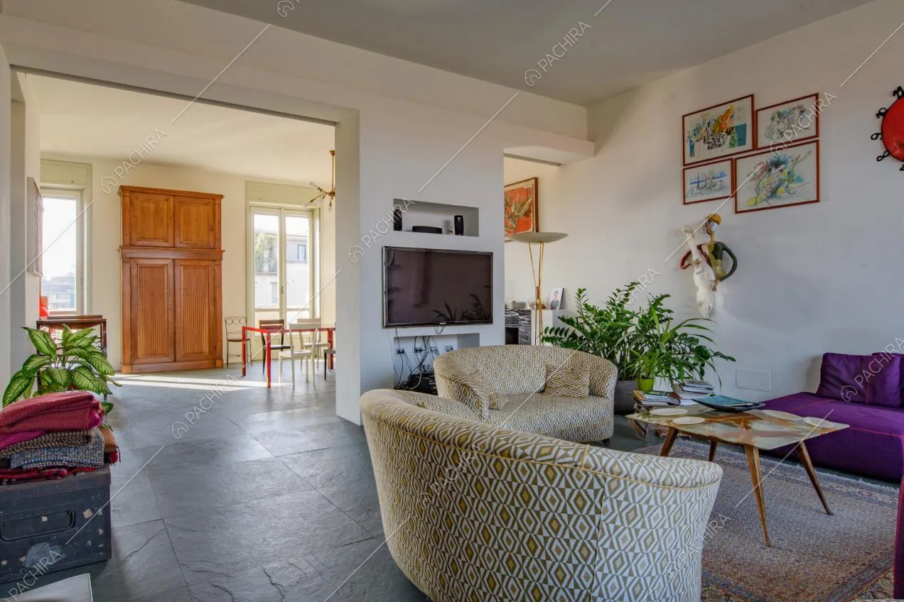 Divani nella luminosa zona living con tavolo da pranzo e pareti bianche