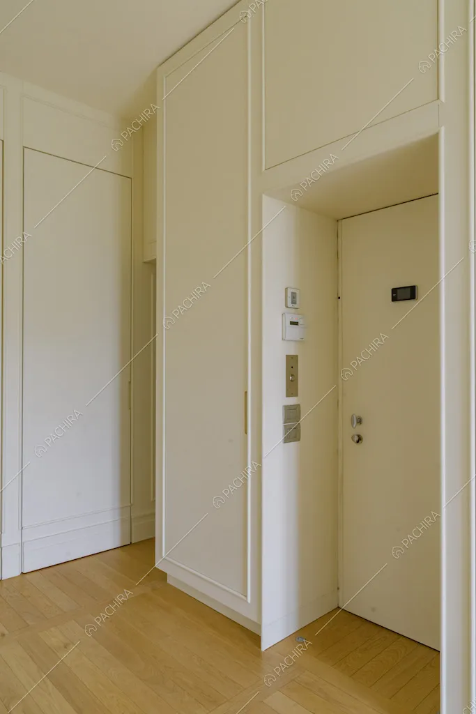 Atrio con porta d'ingresso, pavimento in parquet e pareti bianche