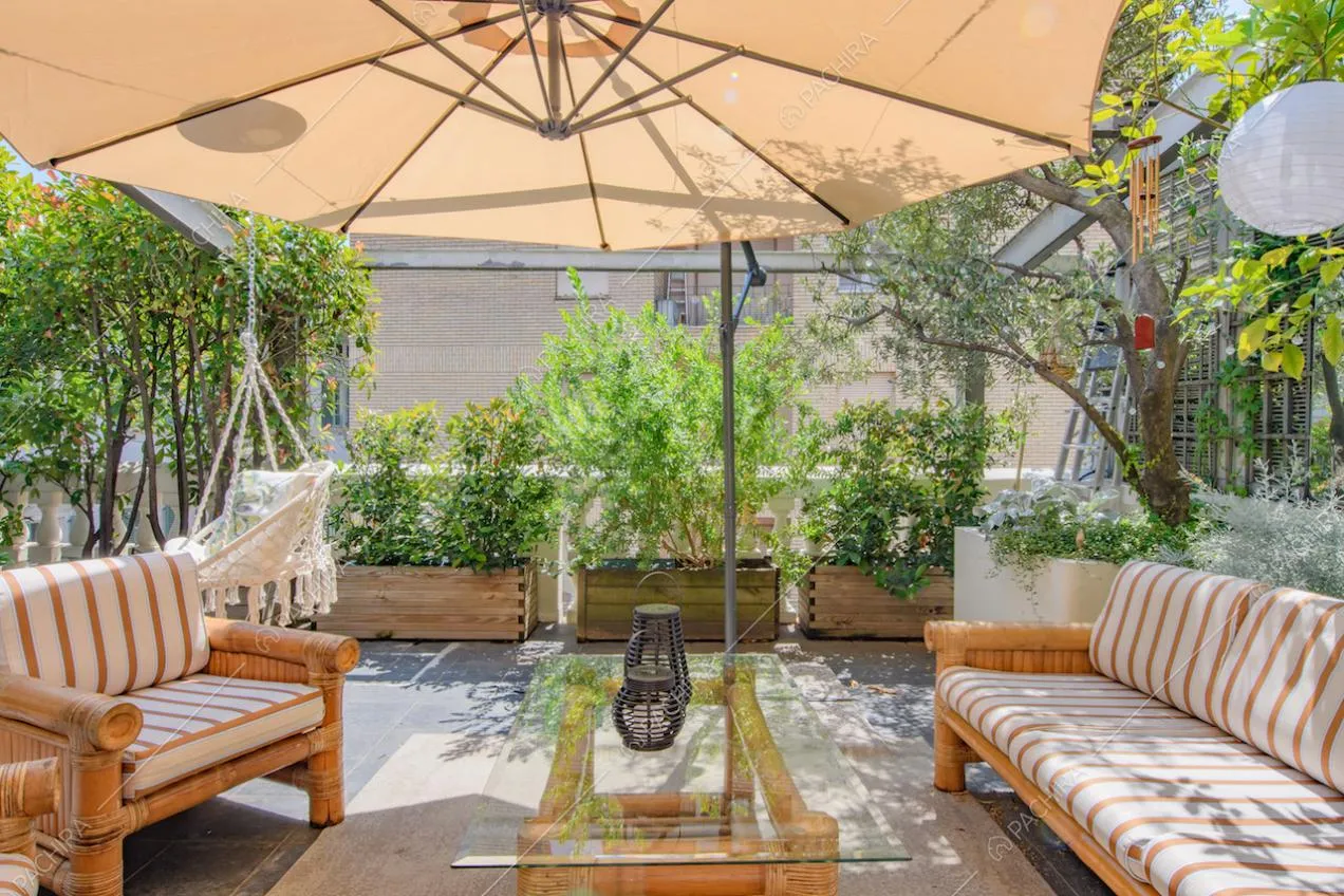 Poltrone e divano da esterni sulla terrazza con piante e ombrellone