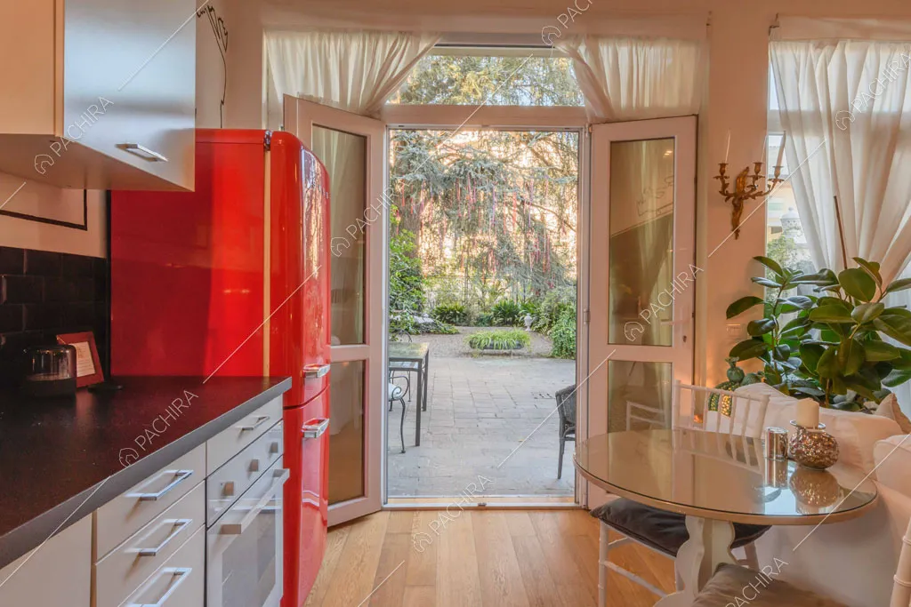 Dalla cucina con piano da lavoro nero vista sul giardino tramite la porta-finestra