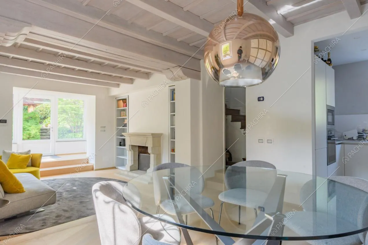 Tavolo da pranzo nel salotto con soffitto in travi in legno bianche e vista sulla cucina