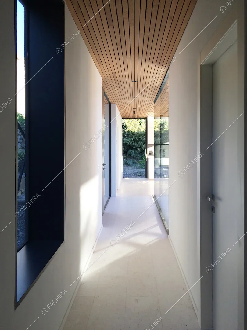 Corridoio della location con pareti e pavimento bianchi e soffitto in legno