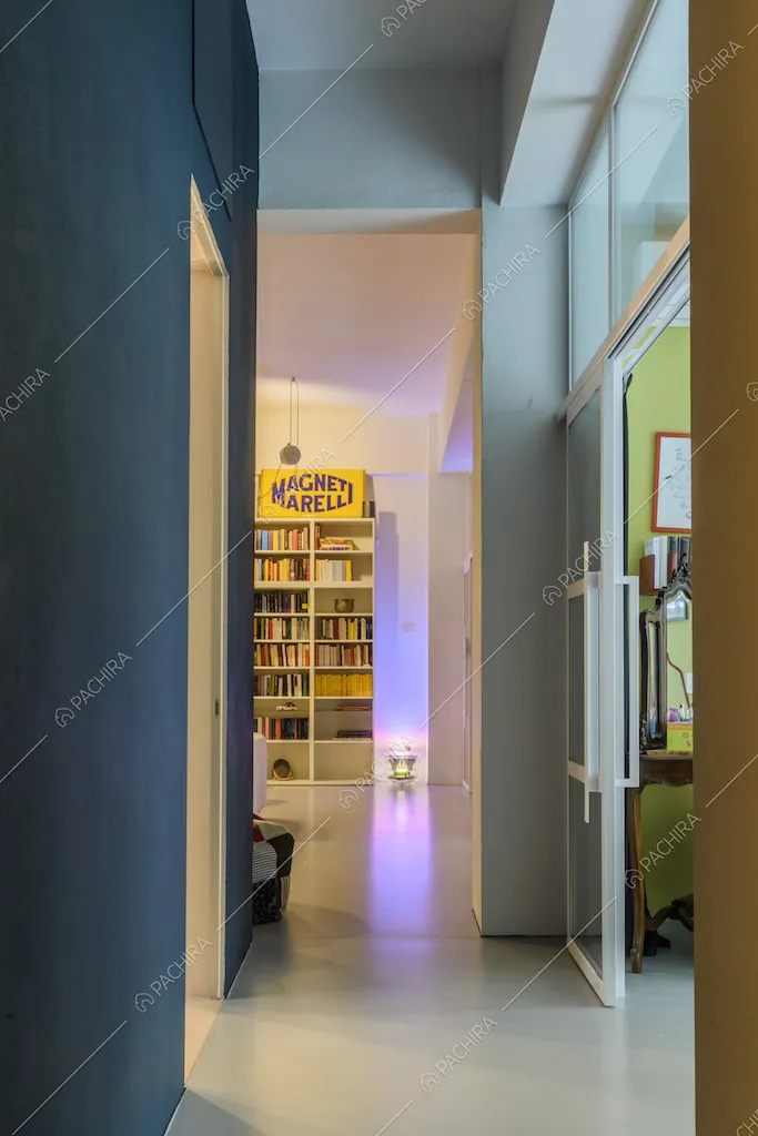 Corridoio con parete blu e vista sulla libreria del soggiorno