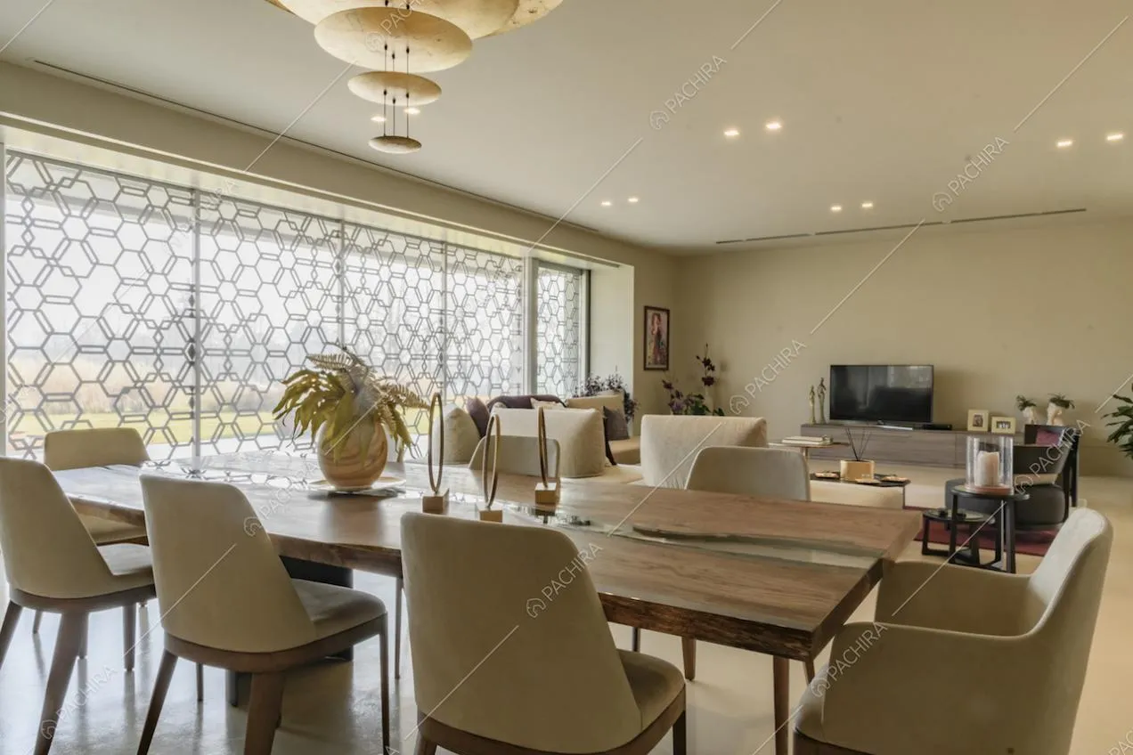 Tavolo da pranzo in legno nella luminosa sala con lampadario di design e pareti beige