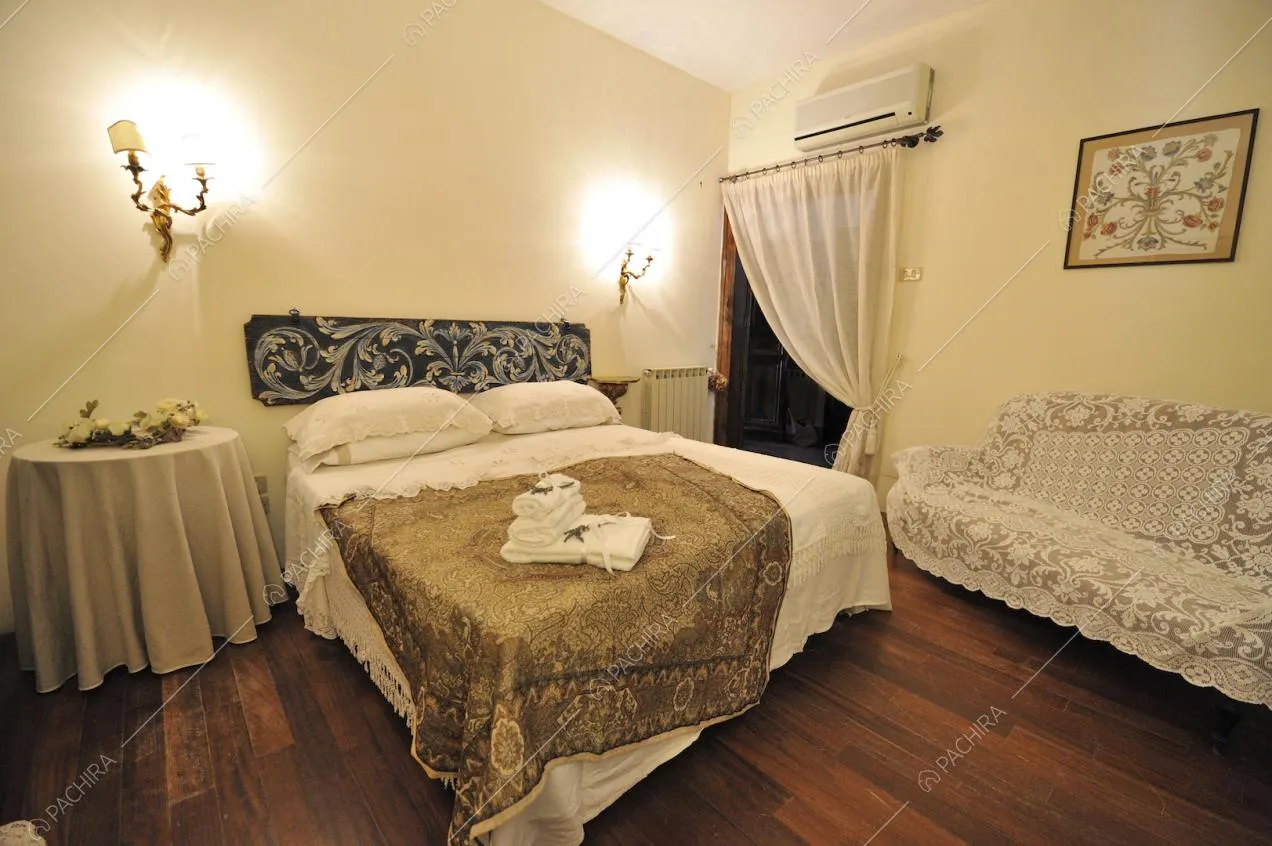 Camera matrimoniale con letto, tavolino tondo e divano rivestito in pizzo