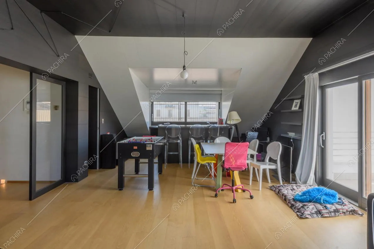 Pavimento in parquet nel solaio con tavolo da pranzo bianco e porte a vetri