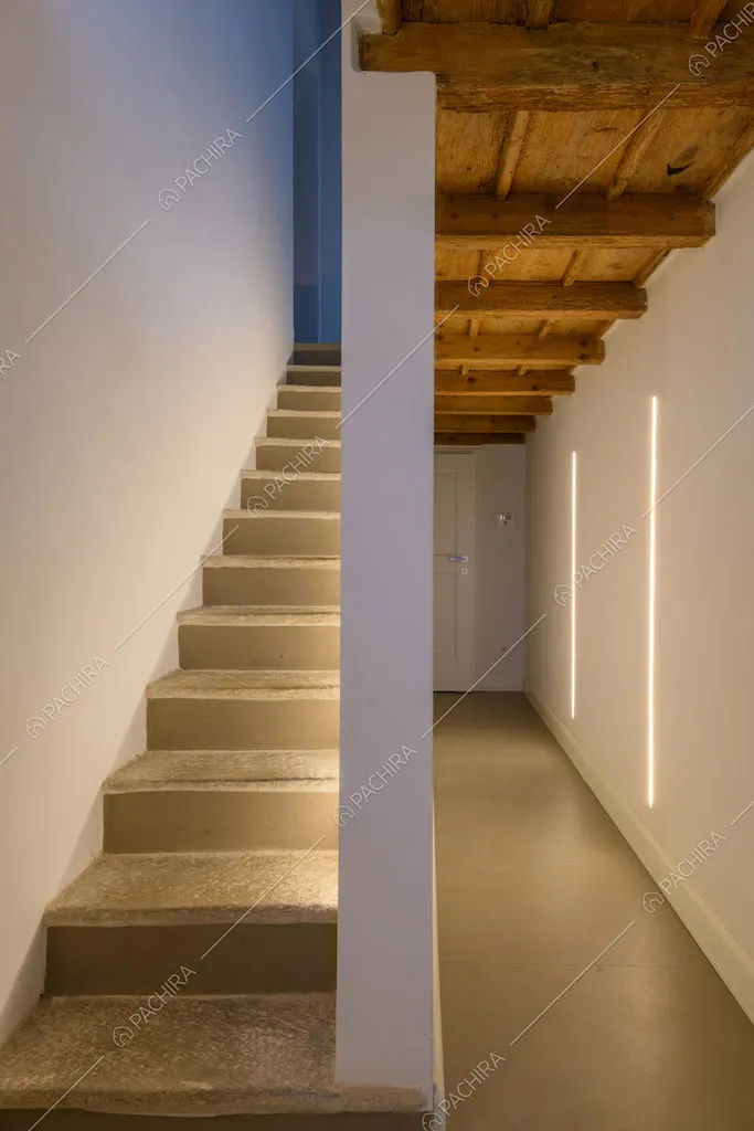 Scale con pareti bianche e vista sul corridoio con pavimento grigio e soffitto a cassettoni
