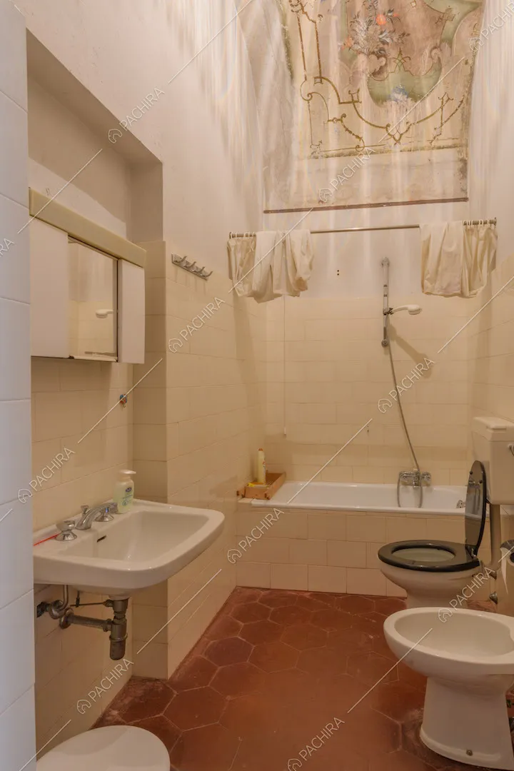 Pavimento in cementine rosse nel bagno con vasca e soffitto affrescato