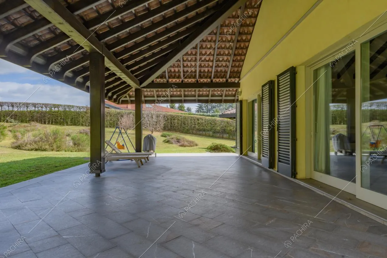 Esterni gialli della villa e grande veranda con travi in legno a vista sul soffitto