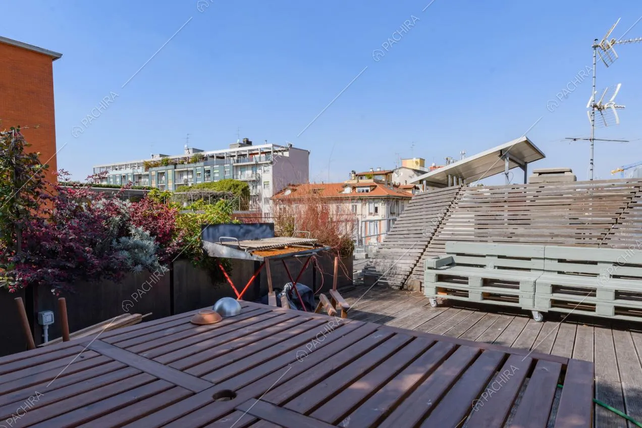 Grande terrazza con tavolo da pranzo in legno, panche e parquet da esterni