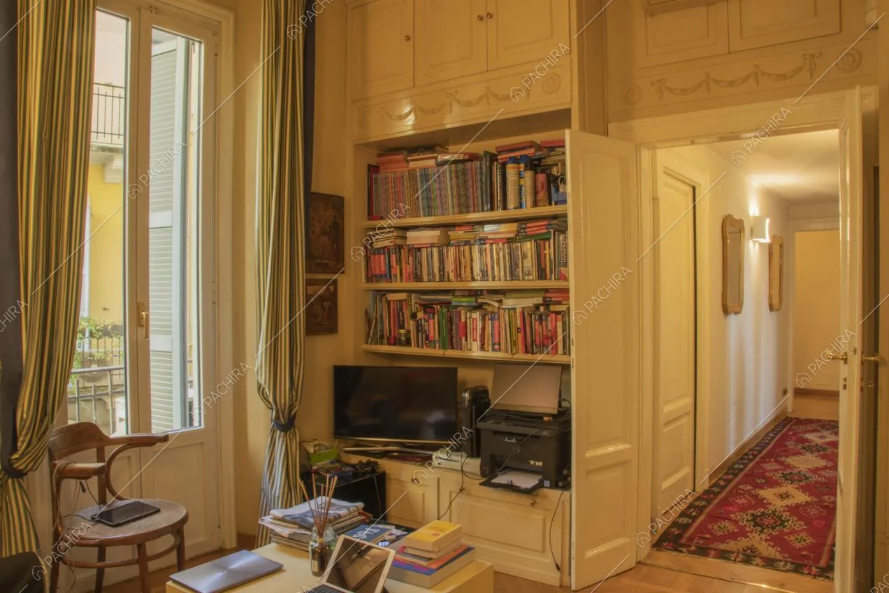Mobile bianco con ripiani pieni di libri e televisore