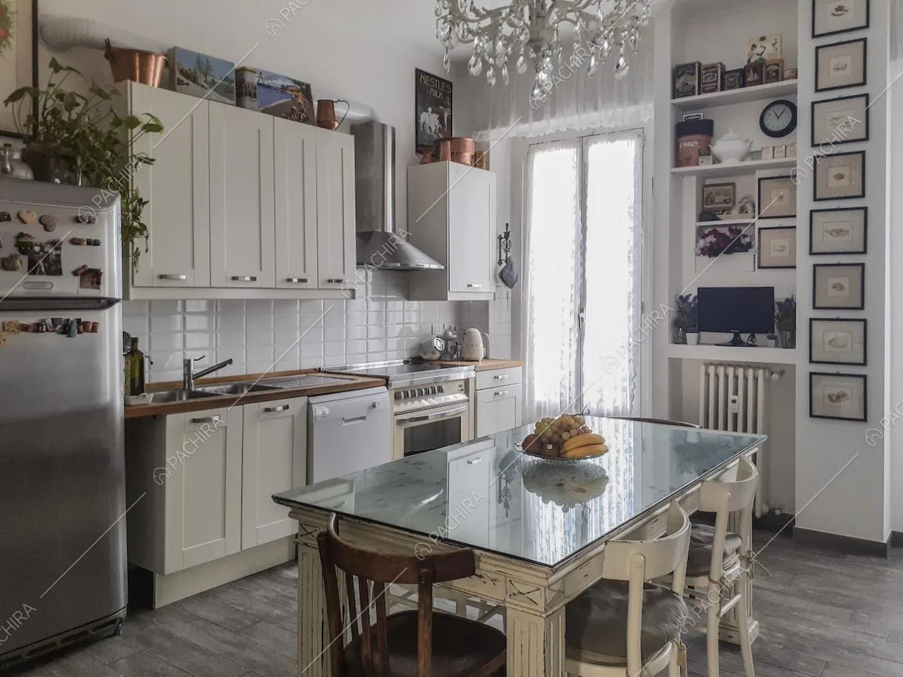 Cucina con mobili bianchi e quadretti appesi alla parete